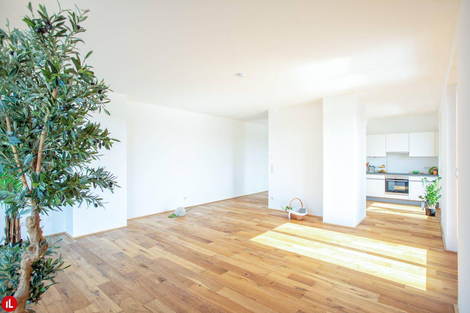 Offener Wohnbereich mit Holzboden und Blick auf die moderne Küche.