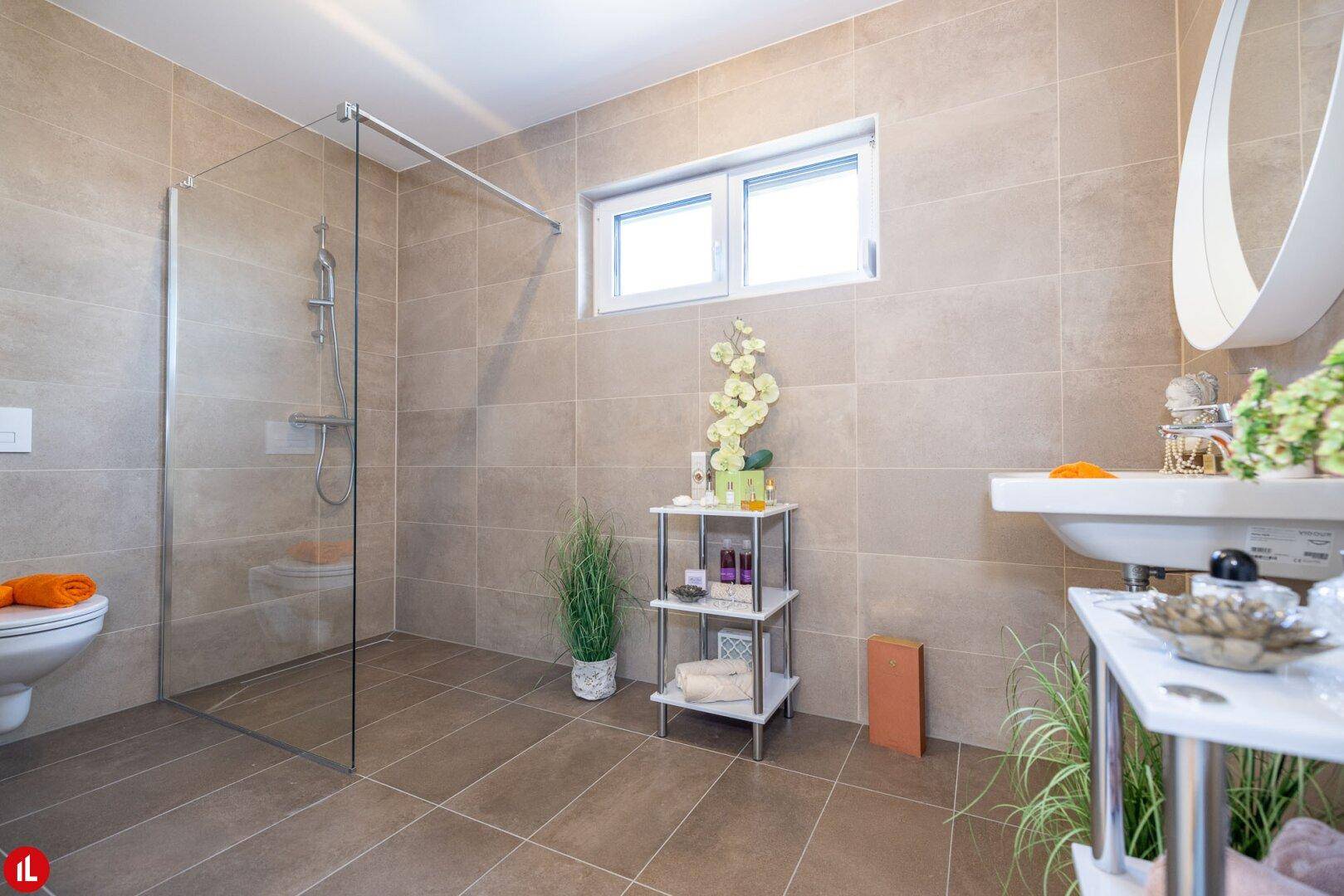 Helles Badezimmer mit beigefarbenen Fliesen, großer begehbarer Dusche und Fenster.