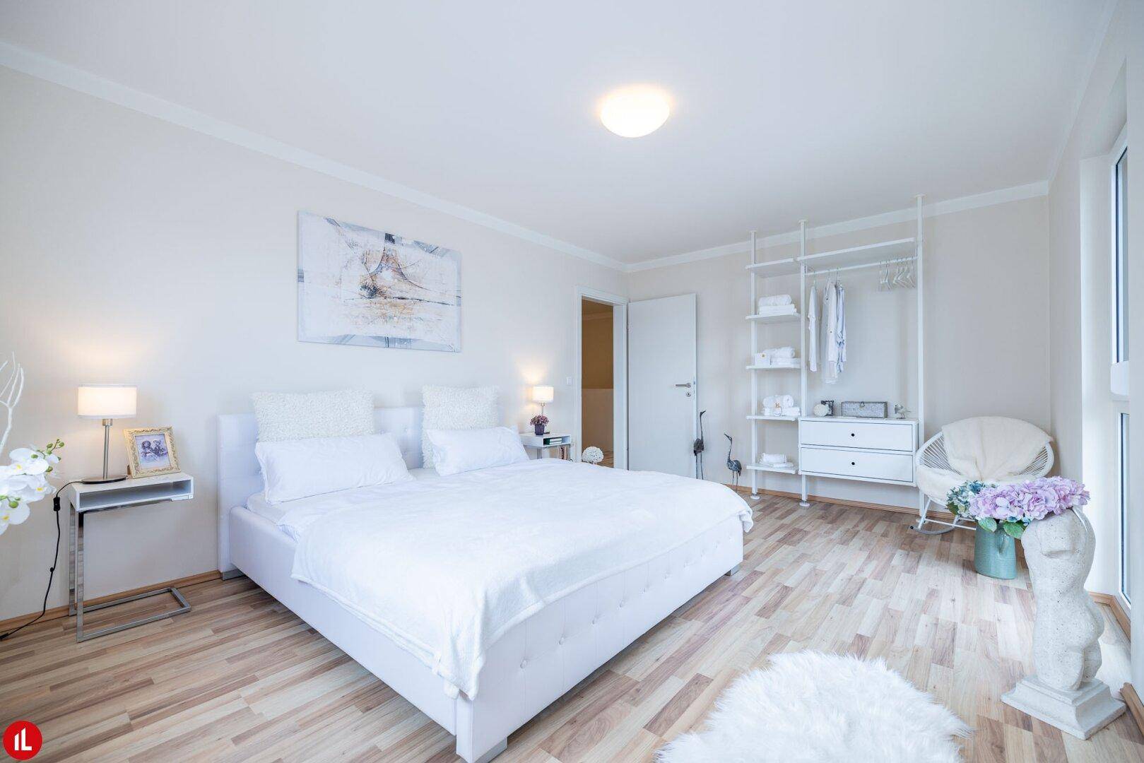 Geräumiges Schlafzimmer mit Doppelbett, hellem Holzboden und offenem Kleiderschrank.