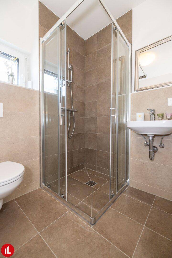 Kompaktes Badezimmer mit Duschkabine, WC, Waschbecken und Fenster für Belüftung.