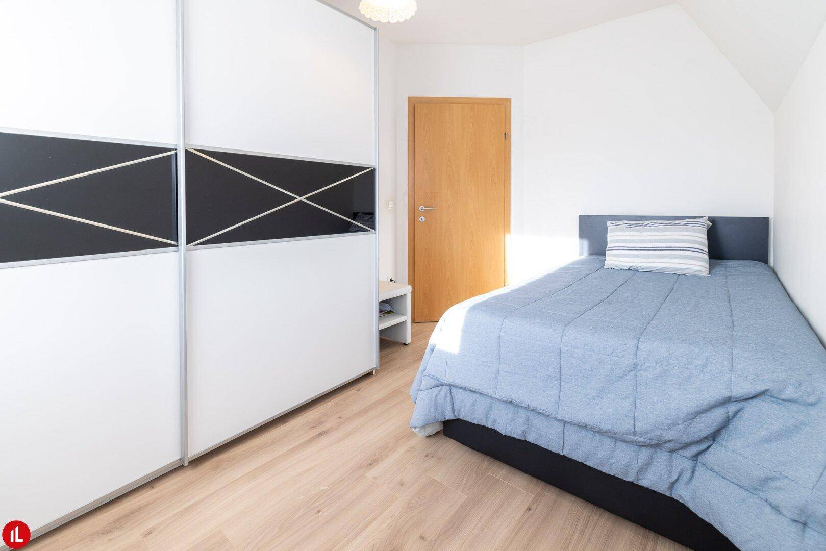 Gemütliches Schlafzimmer mit Einzelbett und modernem Kleiderschrank mit Schiebetüren.