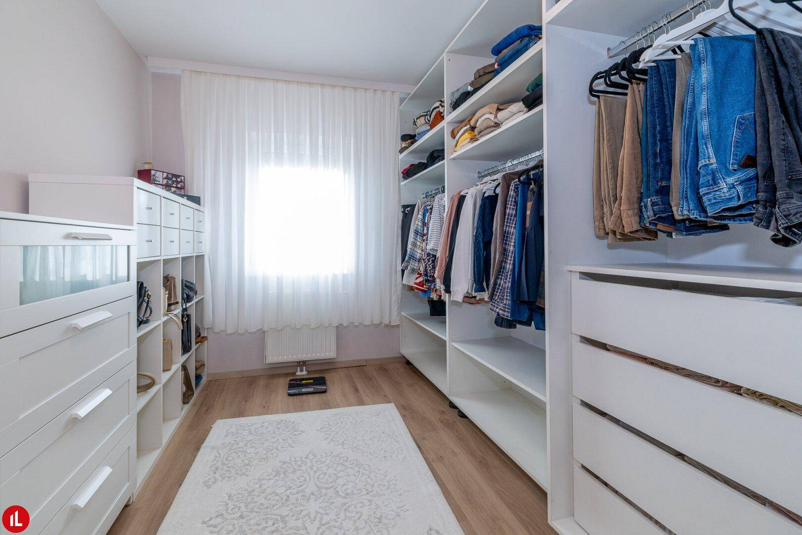 Geräumiger begehbarer Kleiderschrank mit viel Stauraum und natürlichem Lichteinfall.
