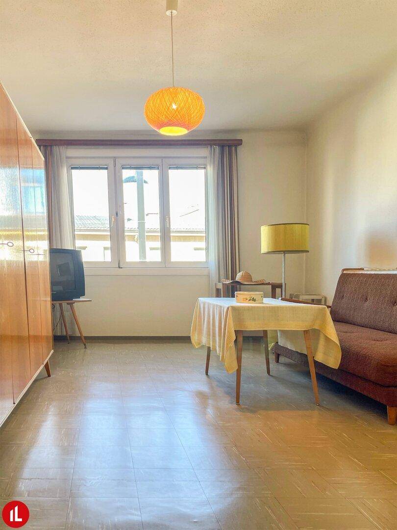 Wohnzimmer mit Vintage-Möbeln, Teppich und großem Fenster für viel Tageslicht.