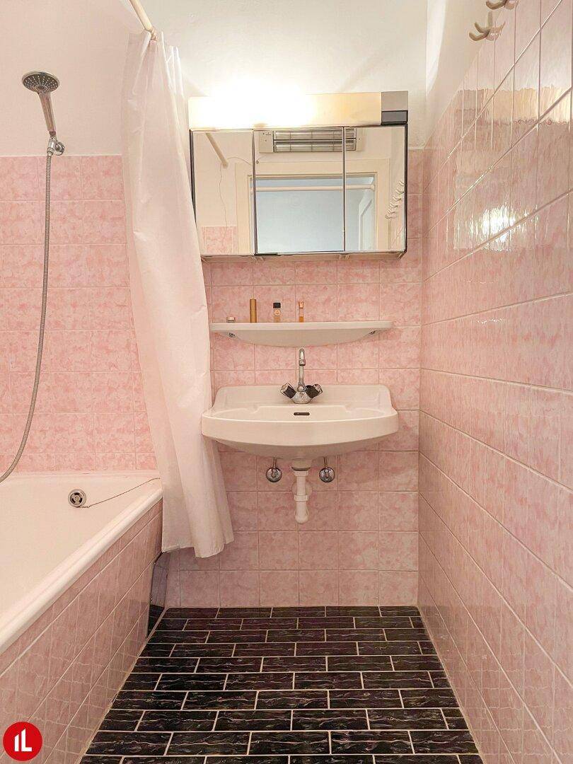 Badezimmer mit rosa Fliesen, Badewanne und Waschbecken, im Stil der 80er Jahre.