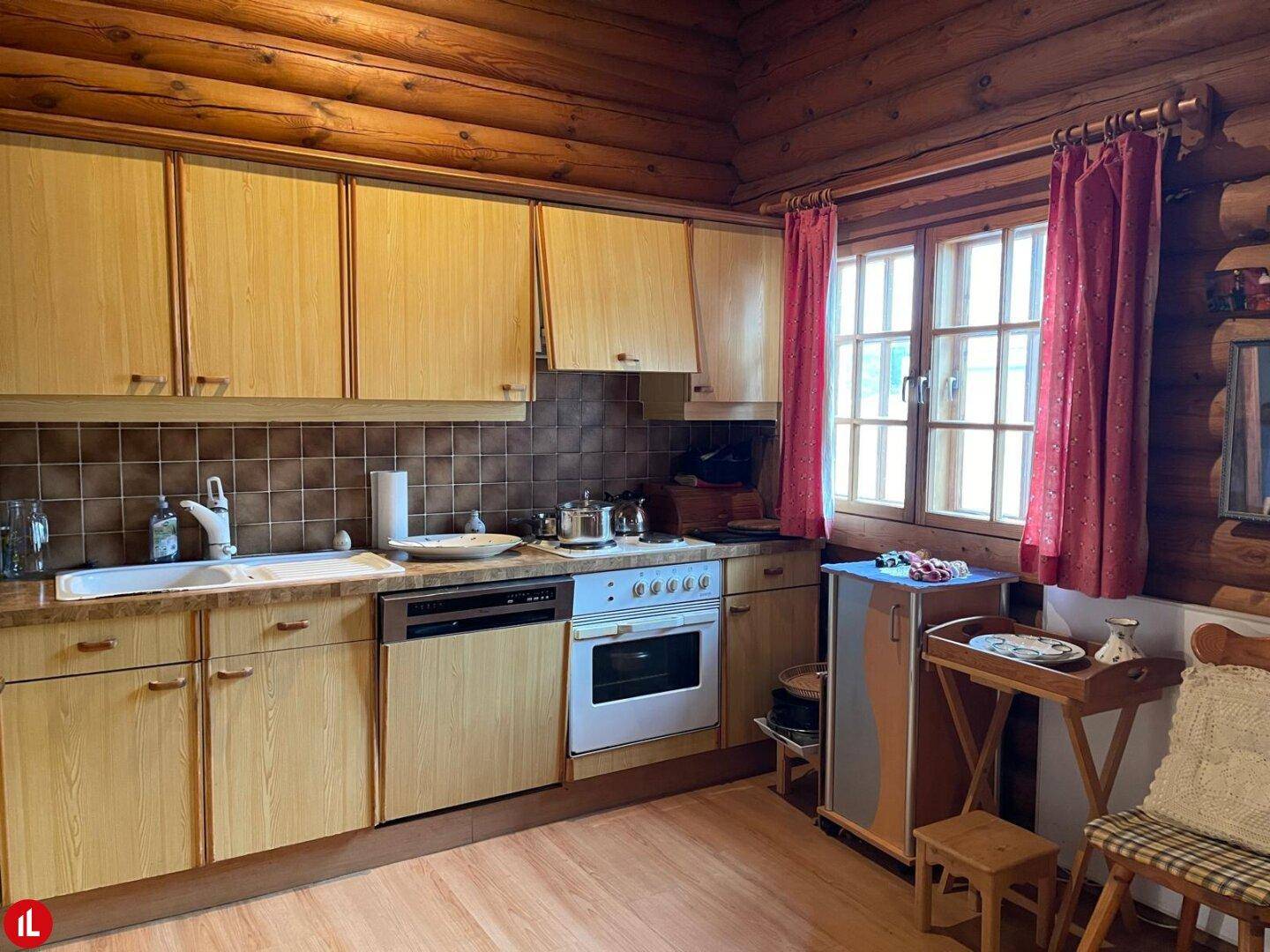 Rustikale Holzküche mit Einbaugeräten, Holzvertäfelung und Fenster mit rotem Vorhang.