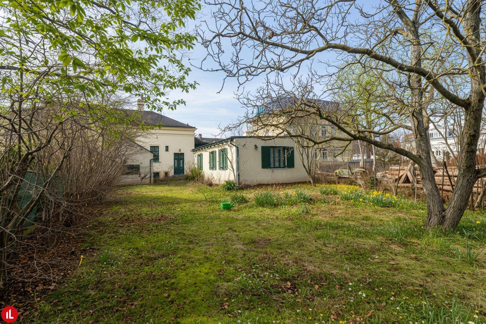 Großer, naturbelassener Garten mit viel Grünfläche und einem Nebengebäude im Hintergrund.