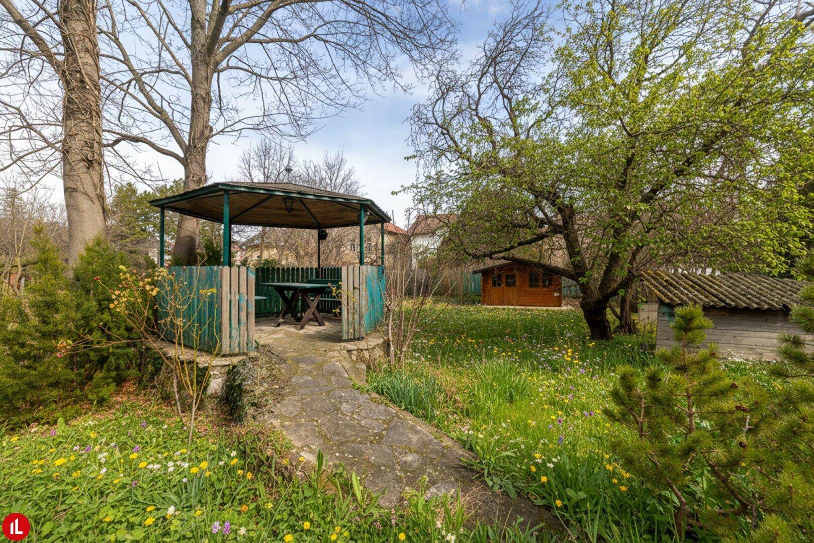 Idyllischer Gartenbereich mit einem Pavillon, Sitzgelegenheiten und einem kleinen Gartenhaus.