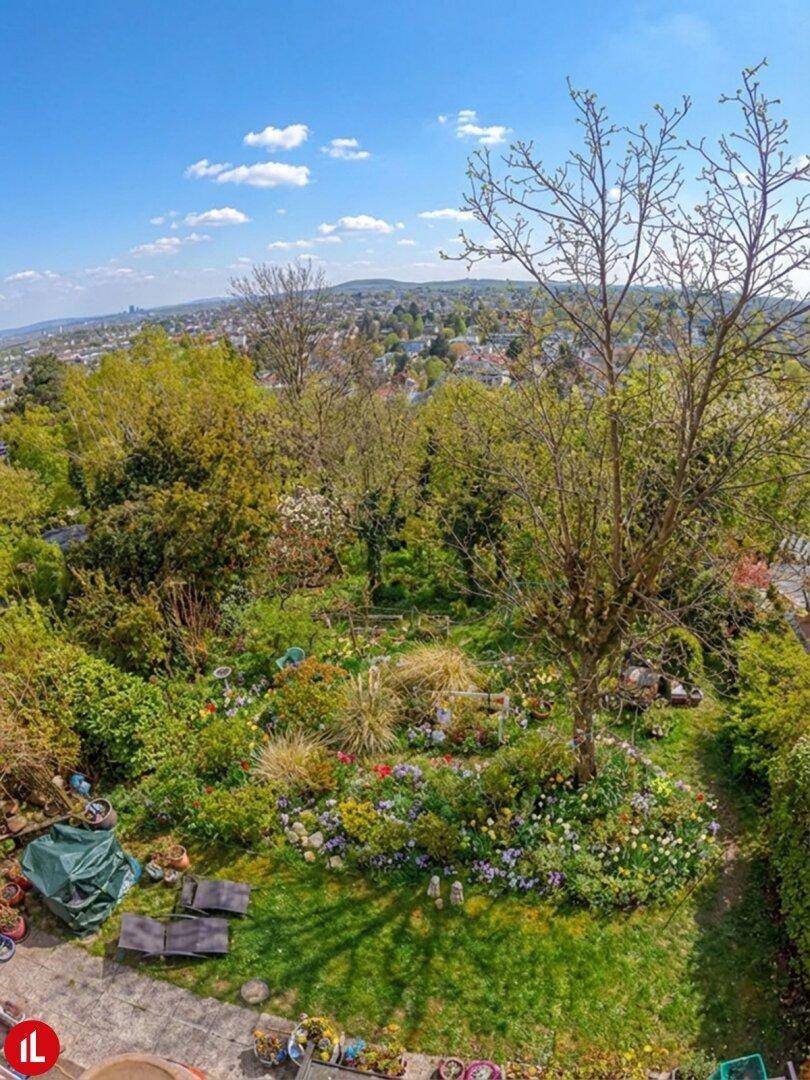 Weitläufiger, üppiger Garten mit vielfältiger Bepflanzung und Panoramablick über die Stadt.