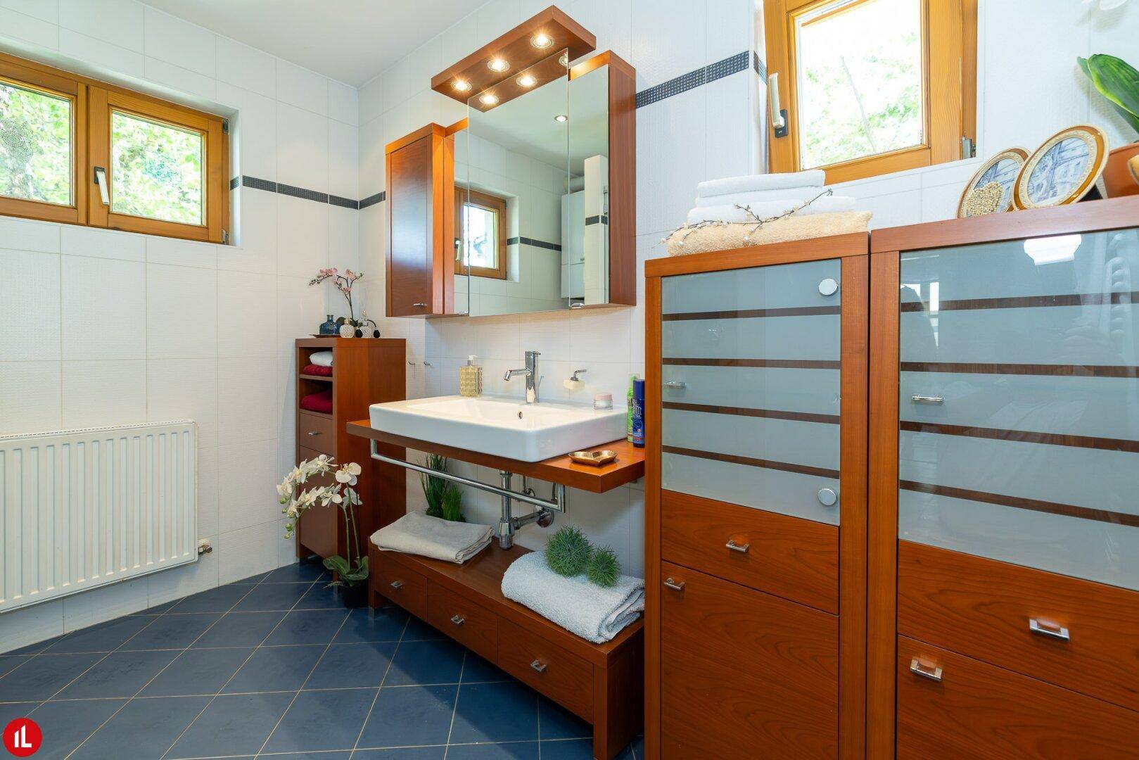 Geräumiges Badezimmer mit Holzmöbeln, großem Waschbecken und Fenster.