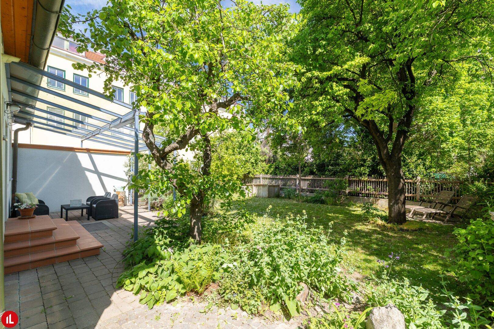Sonnige Terrasse mit Überdachung und Blick in den weitläufigen Garten.