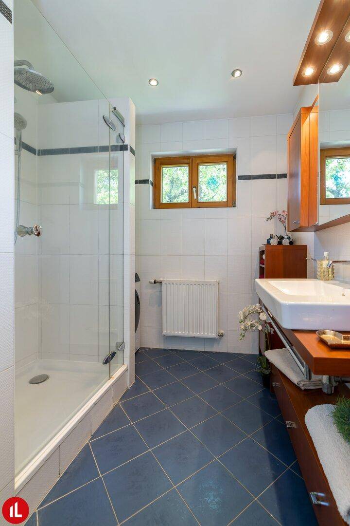 Modernes Badezimmer mit ebenerdiger Dusche, blauen Fliesen und Fenster.