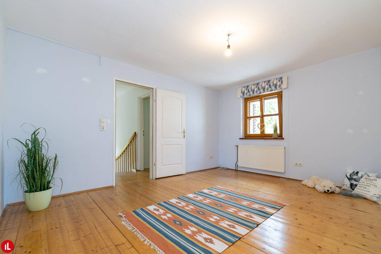 Geräumiges Schlafzimmer mit Holzdielenboden, hellem Anstrich und Fenster.