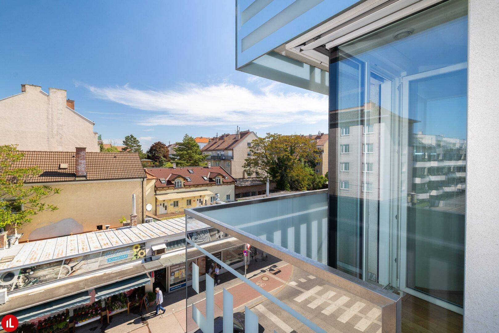 Moderner Balkon mit Glas- und Metallgeländer, bietet einen Blick auf die belebte Straße und die umliegenden Gebäude.