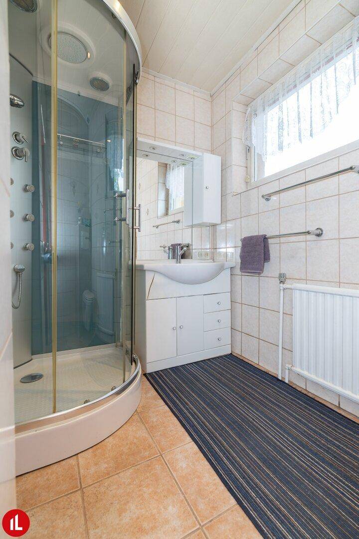 Badezimmer mit Duschkabine, Waschbecken und beigen Fliesen im traditionellen Stil.