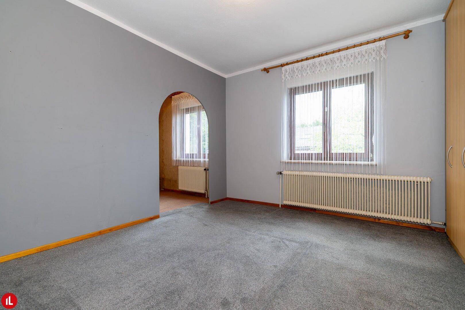 Schlafzimmer mit grauem Teppichboden und zwei Fenstern, bereit zur individuellen Gestaltung.