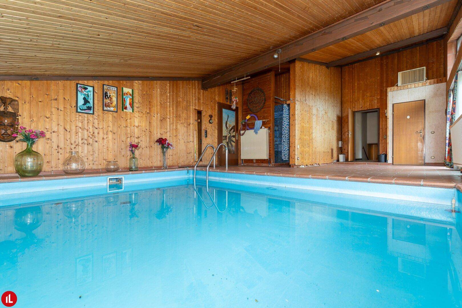 Innenpoolbereich mit Holzverkleidung, Fliesenboden und Zugang zu weiteren Räumen.