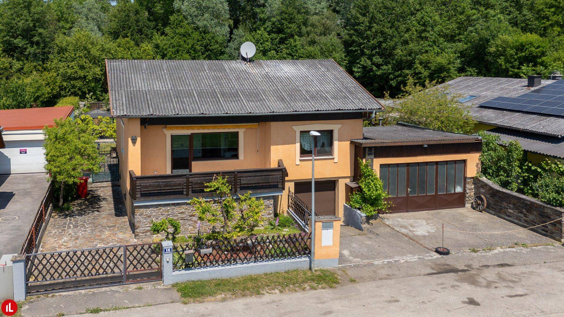 Ansicht des Hauses von der Straße mit Vorgarten, Einfahrt und Balkon.