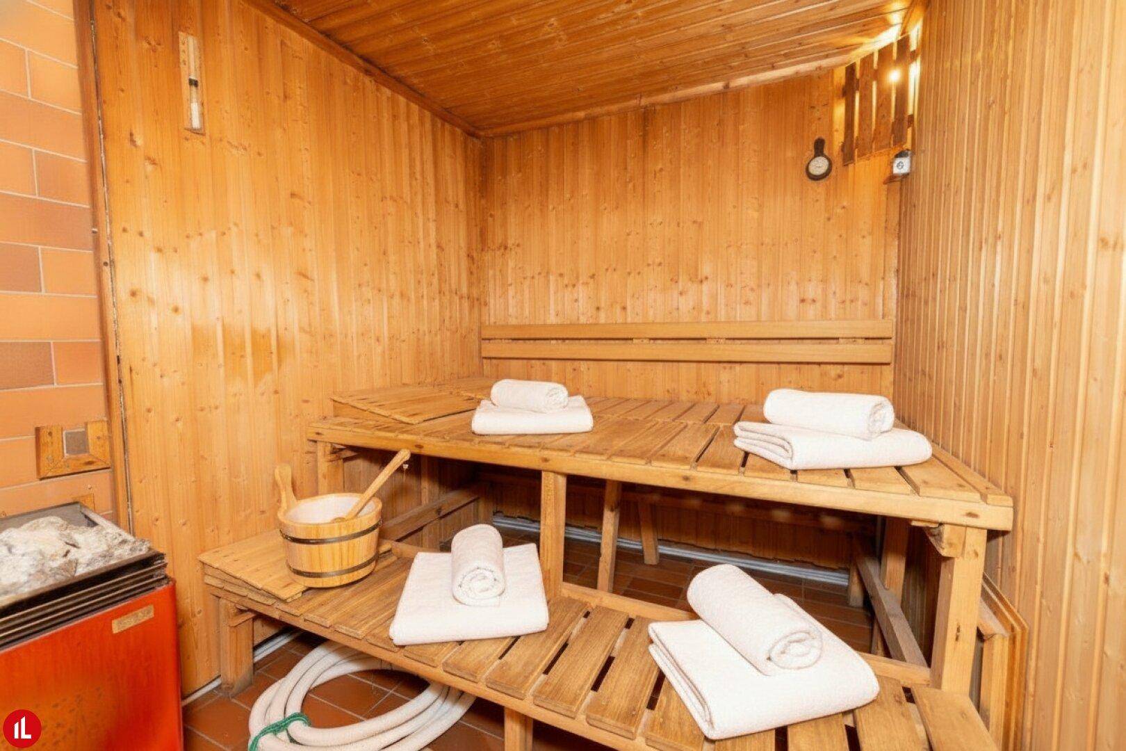 Gemütliche Holzsauna mit Handtüchern und traditionellem Aufguss-Zubehör.