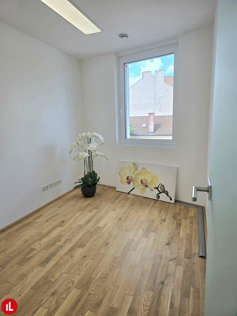 Gemütlicher Raum mit Holzboden, einem Fenster und einer Orchideendekoration.