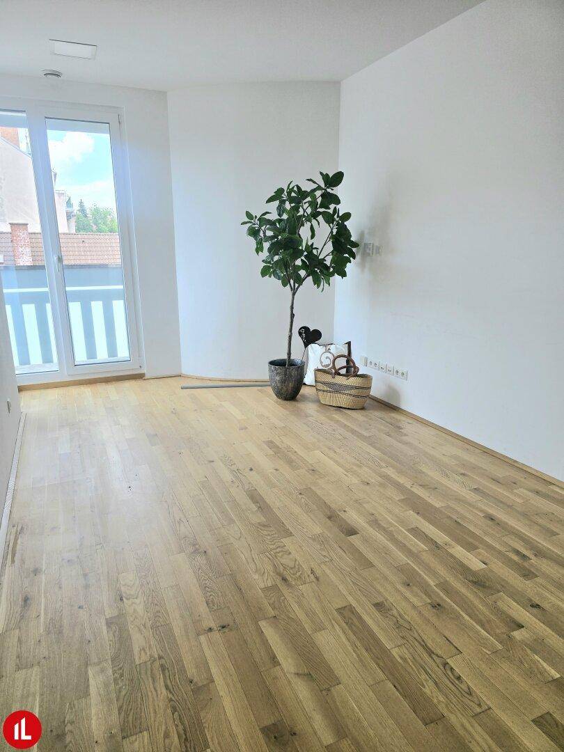 Geräumiger Wohnbereich mit Holzboden und Zugang zu einem Balkon, ideal für natürliches Licht.