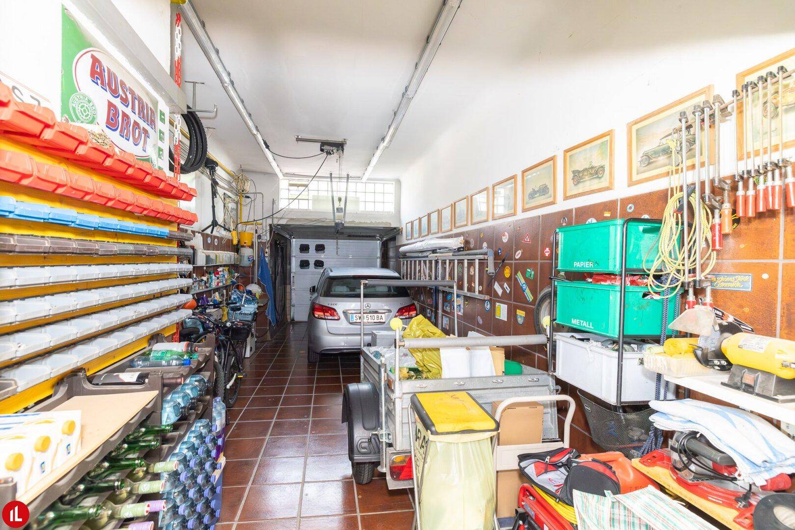 Geräumige Garage mit einem geparkten Auto, Werkzeugen und Lagerregalen.