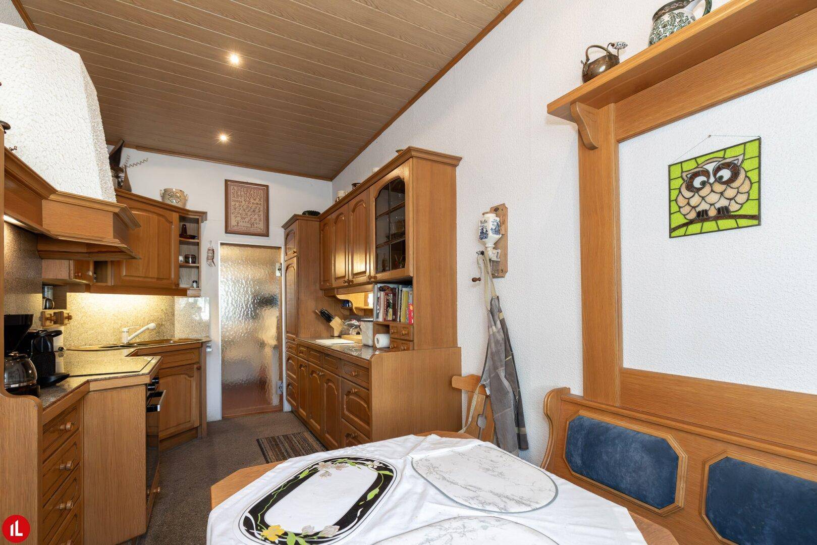 Traditionelle Holzküche mit Einbauschränken, Essbereich und Holzdeckenverkleidung.