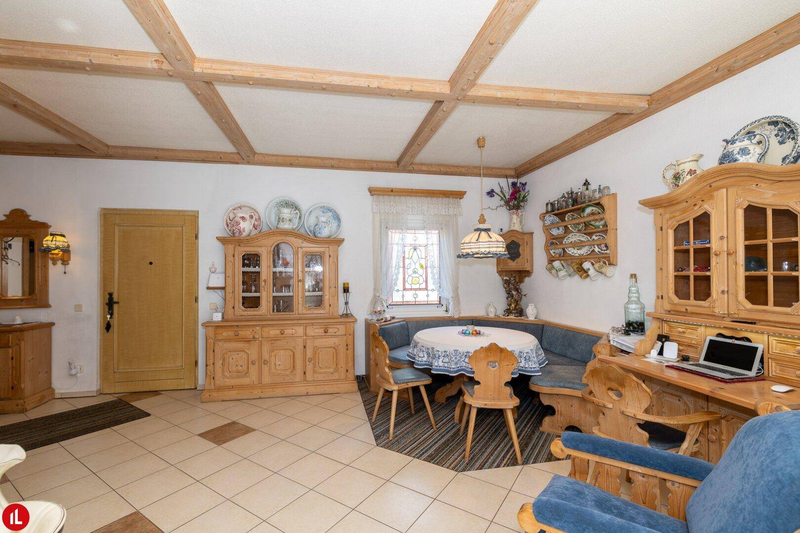 Gemütlicher Wohn-Essbereich im Landhausstil mit Holzbalkendecke, Fliesenboden und traditionellen Möbeln.