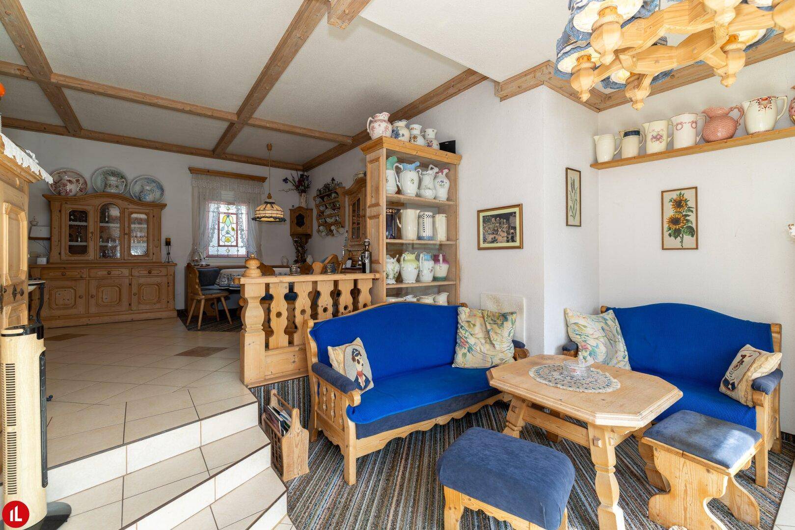 Rustikales Wohnzimmer mit blauen Sofas, Holzbalkendecke und traditionellen Dekorationen.