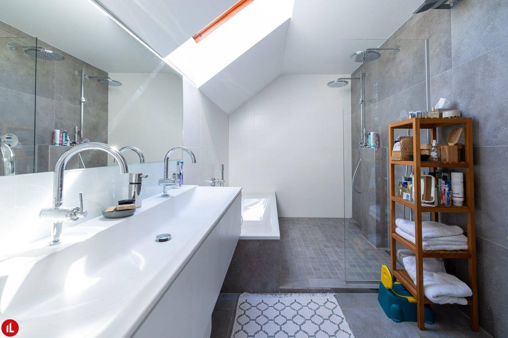 Modernes Badezimmer mit Doppelwaschbecken, begehbarer Dusche und Dachfenster.