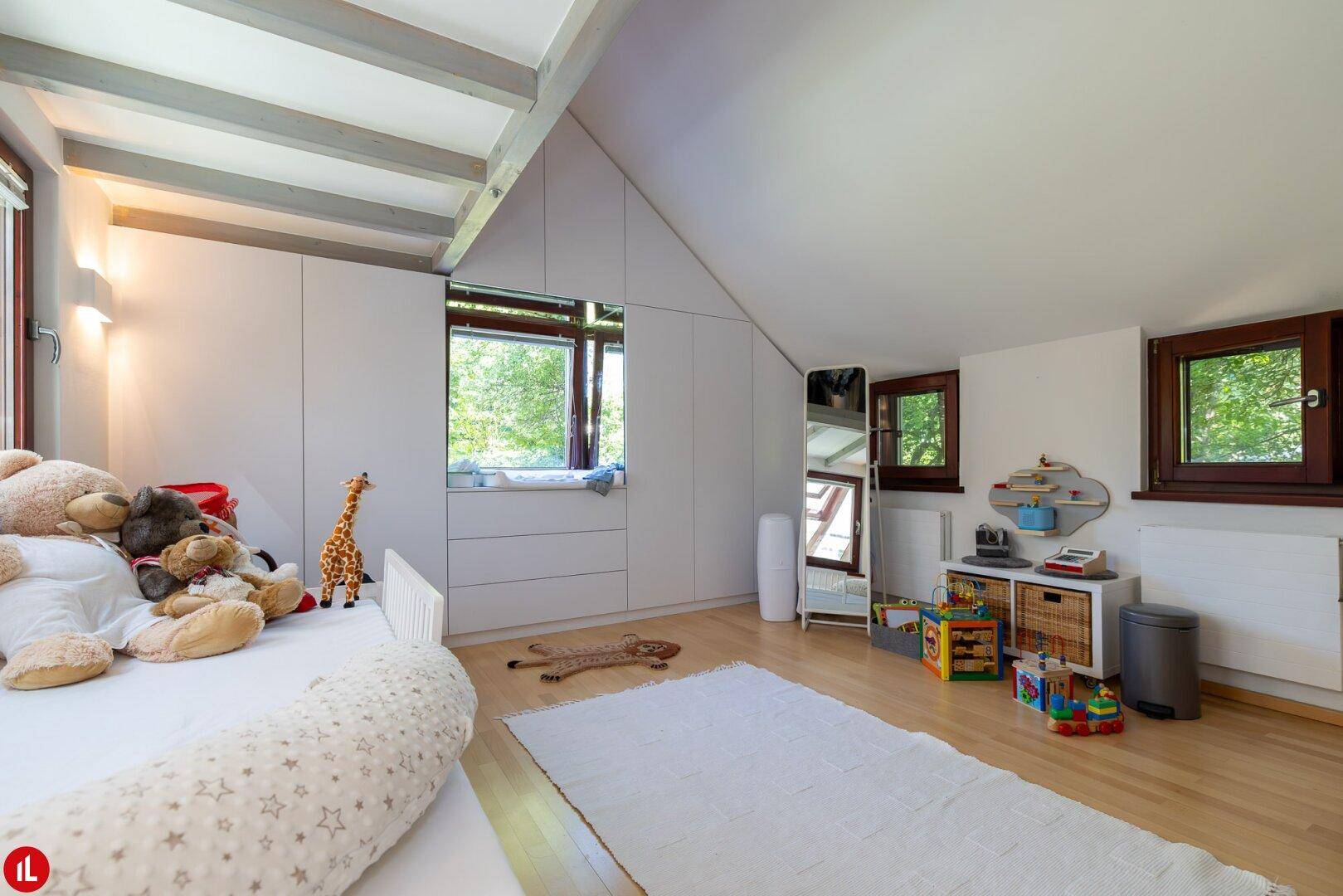 Kinderzimmer im Dachgeschoss mit Dachschräge, Einbauschränken und Holzboden.