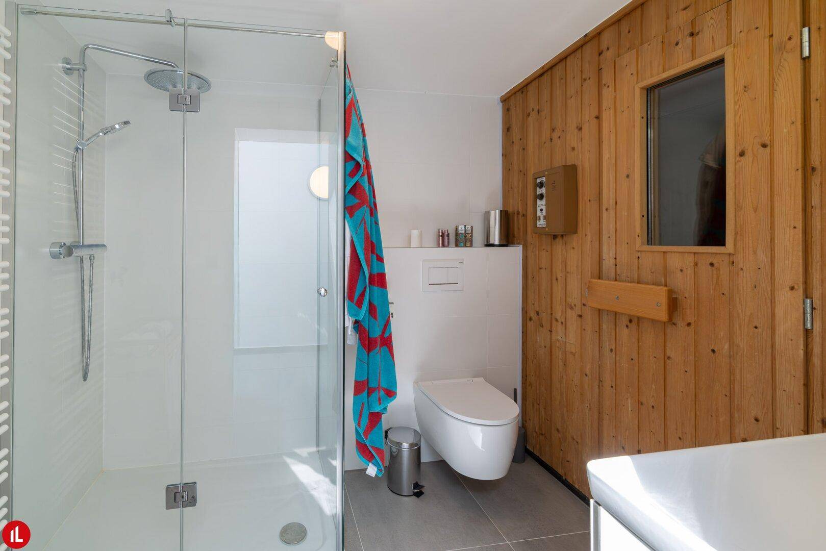 Modernes Badezimmer mit begehbarer Dusche, WC und integrierter Sauna.