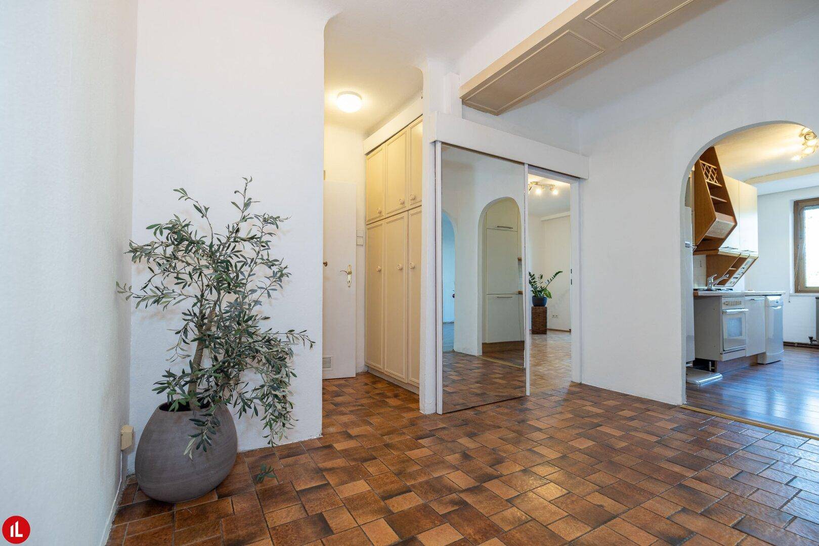Heller Eingangsbereich mit Terrakotta-Fliesenboden, Einbauschränken und Blick in den Wohnbereich.