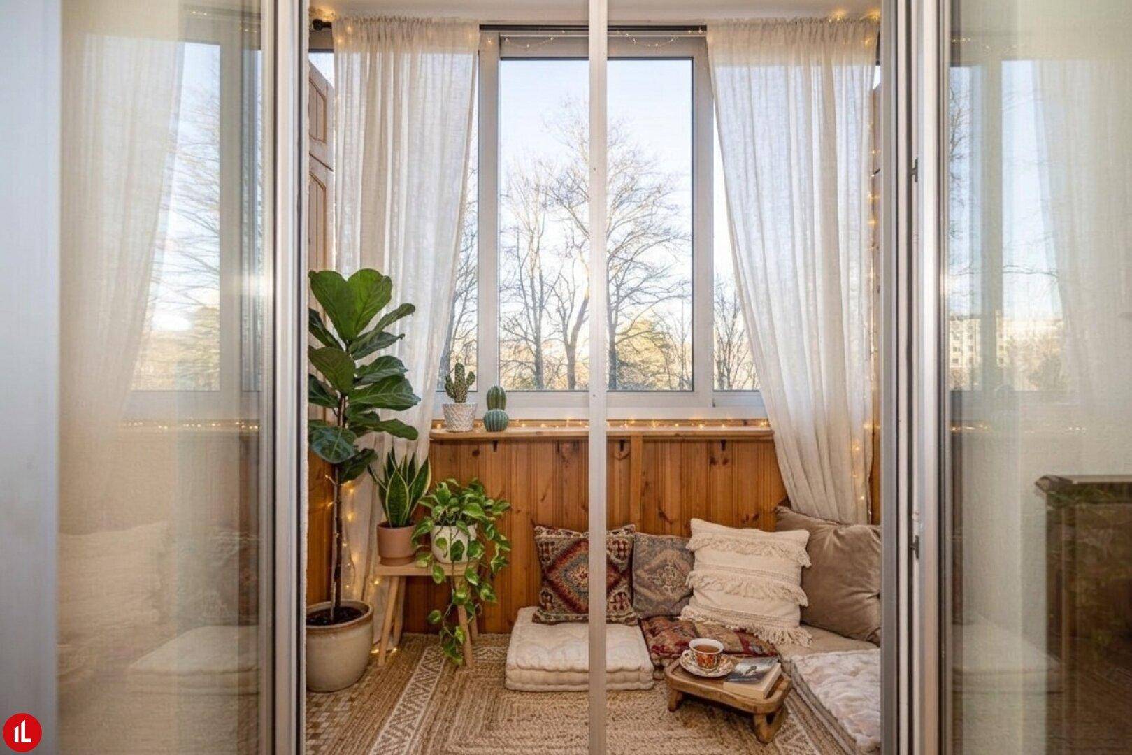 Gemütlicher Wintergarten mit Holzwänden, vielen Pflanzen und bequemen Kissen für eine entspannte Atmosphäre.