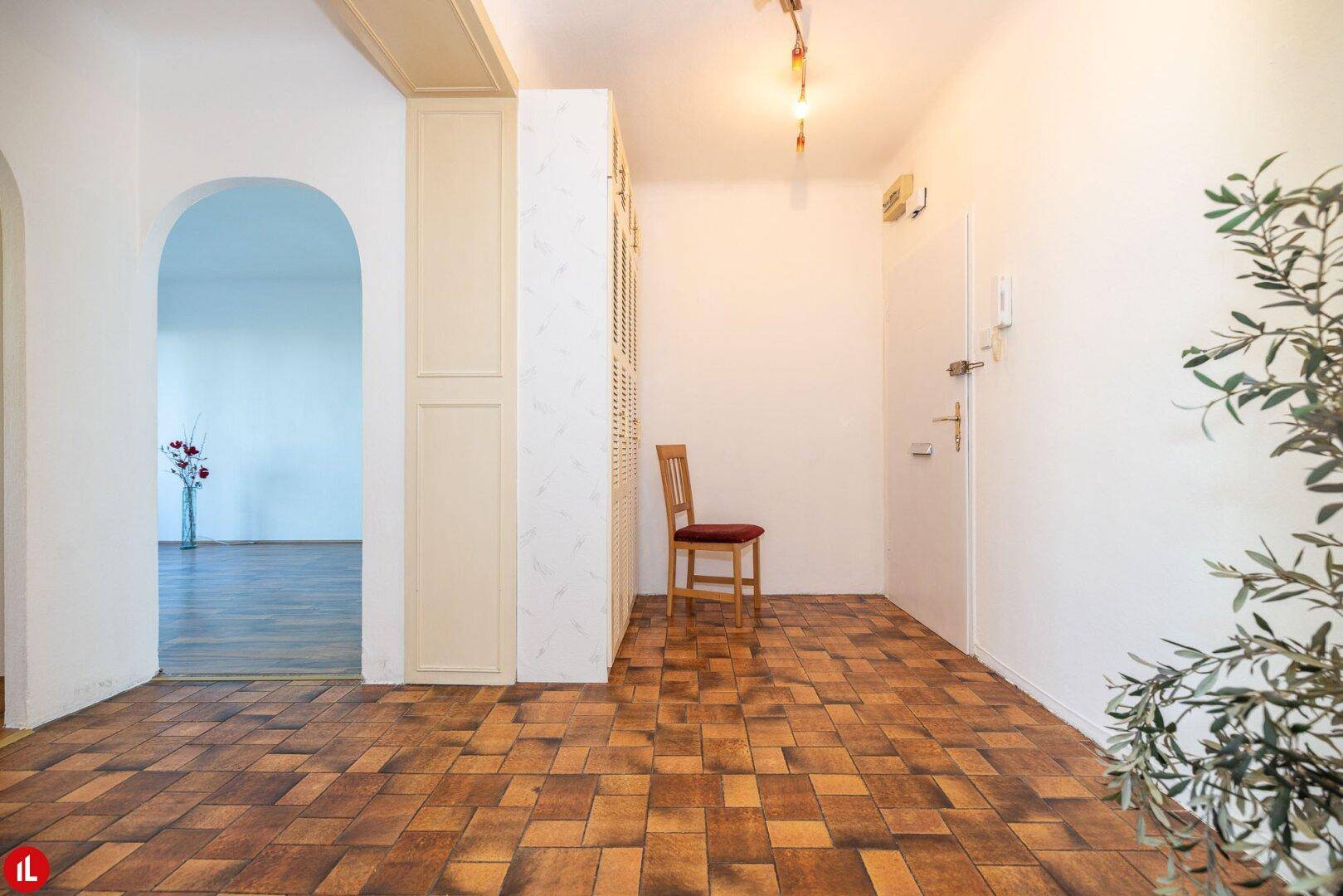 Eingangsbereich mit Haustür, Terrakotta-Fliesenboden und integrierten Schränken, die Stauraum bieten.