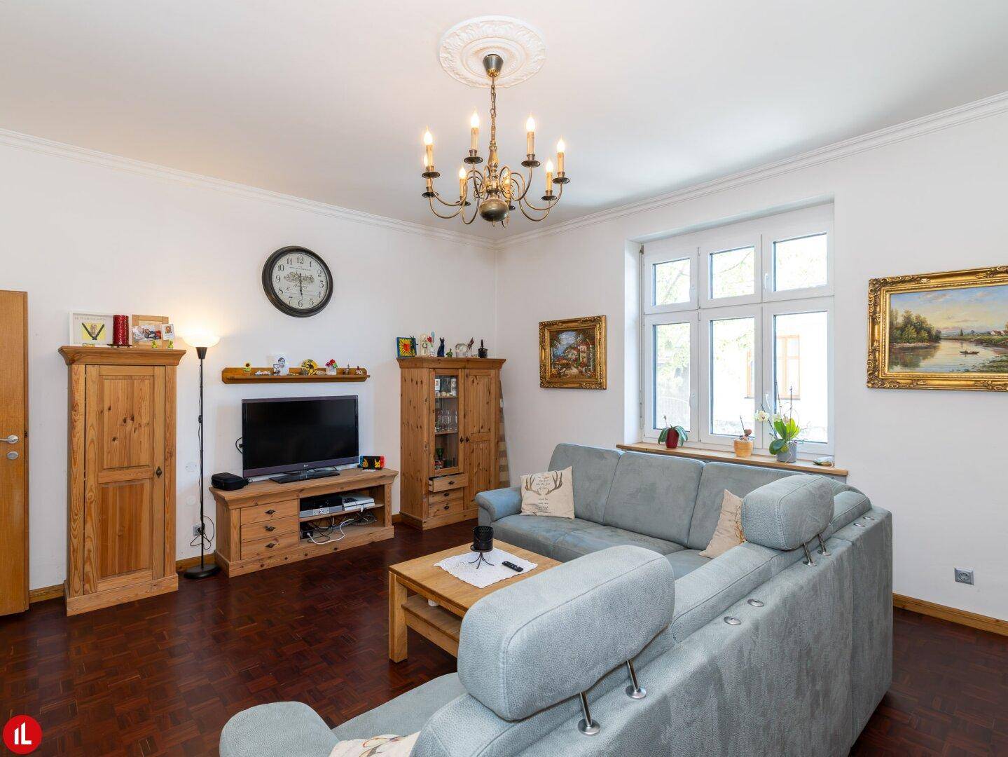 Gemütliches Wohnzimmer mit großem Sofa, Holzmöbeln und einem Kronleuchter an der Decke.
