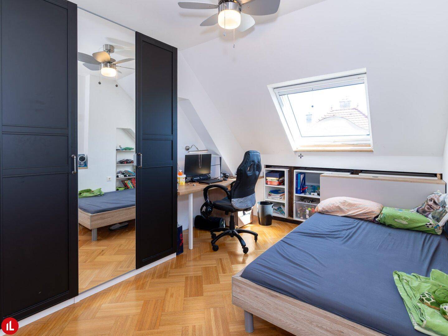 Kinderzimmer mit Spiegelschrank, Schreibtischbereich und Dachfenster, das viel Licht spendet.