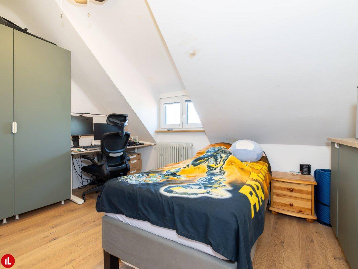 Weiteres Schlafzimmer mit Einzelbett, Schreibtisch, Kleiderschrank und kleinem Fenster im Dachgeschoss.