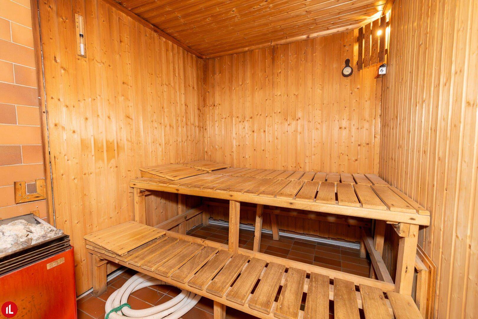 Traditionelle Holzsauna mit mehrstufigen Bänken und Saunaofen, ideal für entspannende Wellnessmomente.