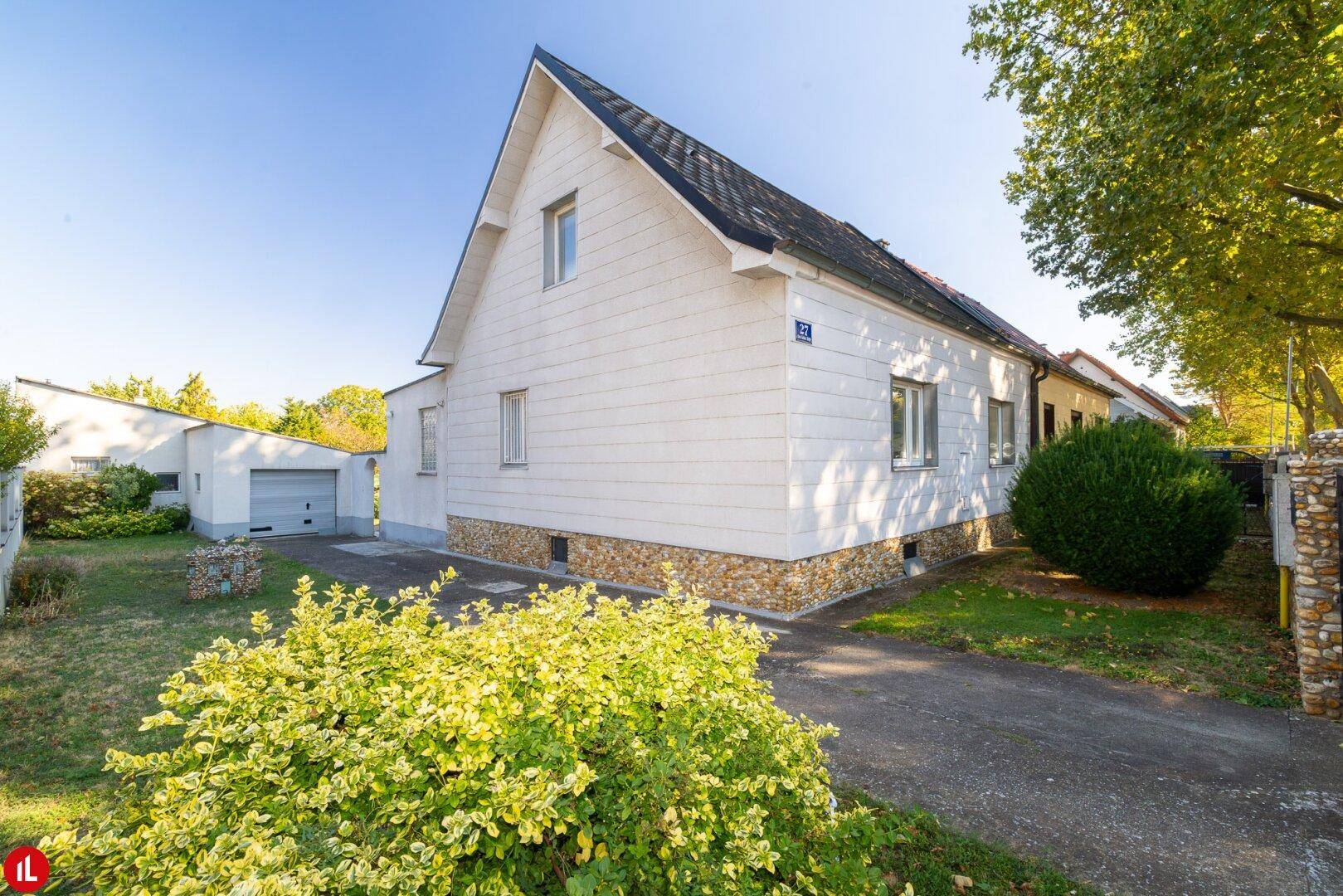 Seitenansicht des Einfamilienhauses mit gepflegtem Vorgarten und Zufahrt zur Garage.