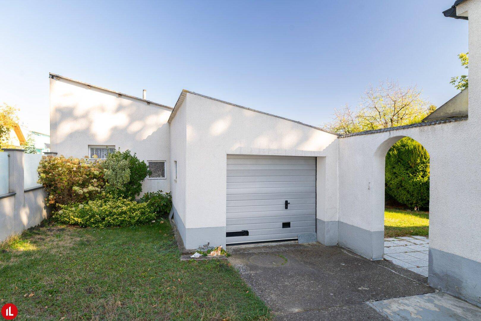 Separate Garage mit modernem Tor und angrenzendem kleinen Rasenbereich.