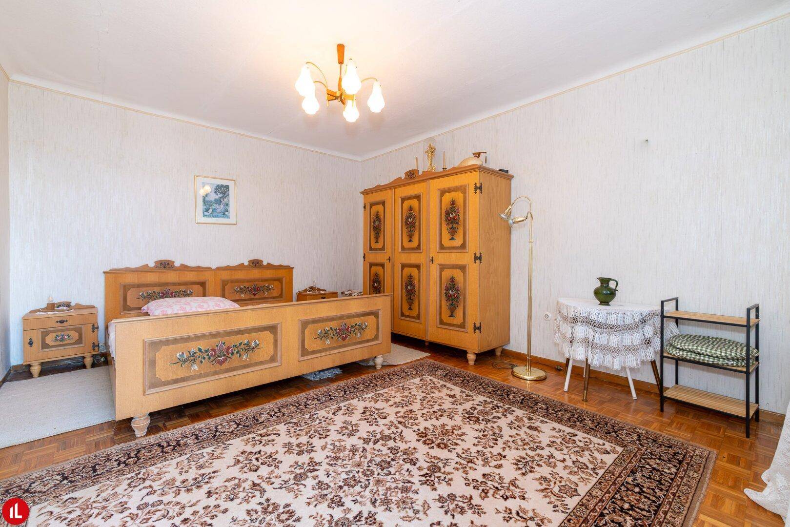 Geräumiges Schlafzimmer mit traditionellen Holzmöbeln, Teppich und Parkettboden.