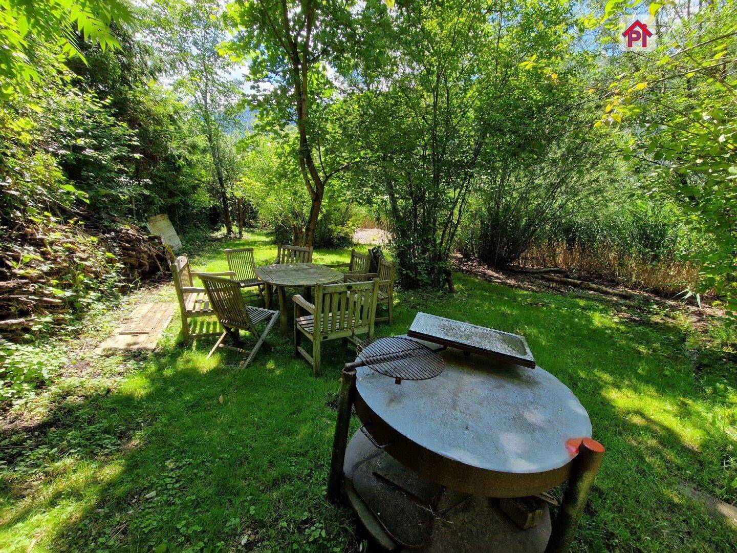 Gemütlicher Grillplatz im Garten mit Sitzgelegenheiten und einem Holzkohlegrill.