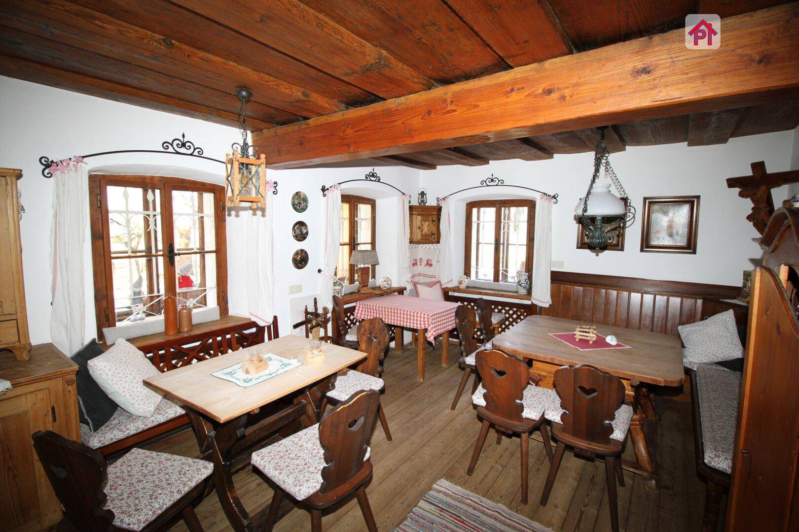 Rustikaler Speisesaal mit Holztischen, Bänken und sichtbaren Deckenbalken, der eine gemütliche Atmosphäre schafft.
