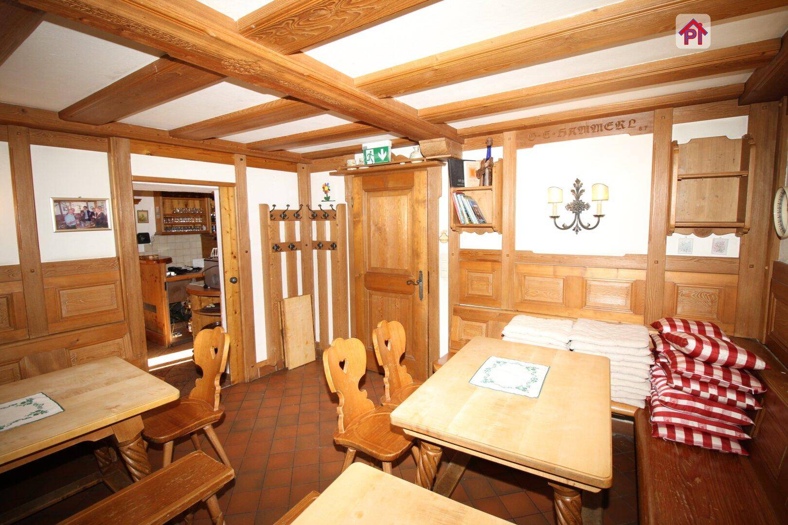 Gemütlicher Essbereich mit Holztischen, Bänken und einer umfassenden Holzvertäfelung an Wänden und Decke.