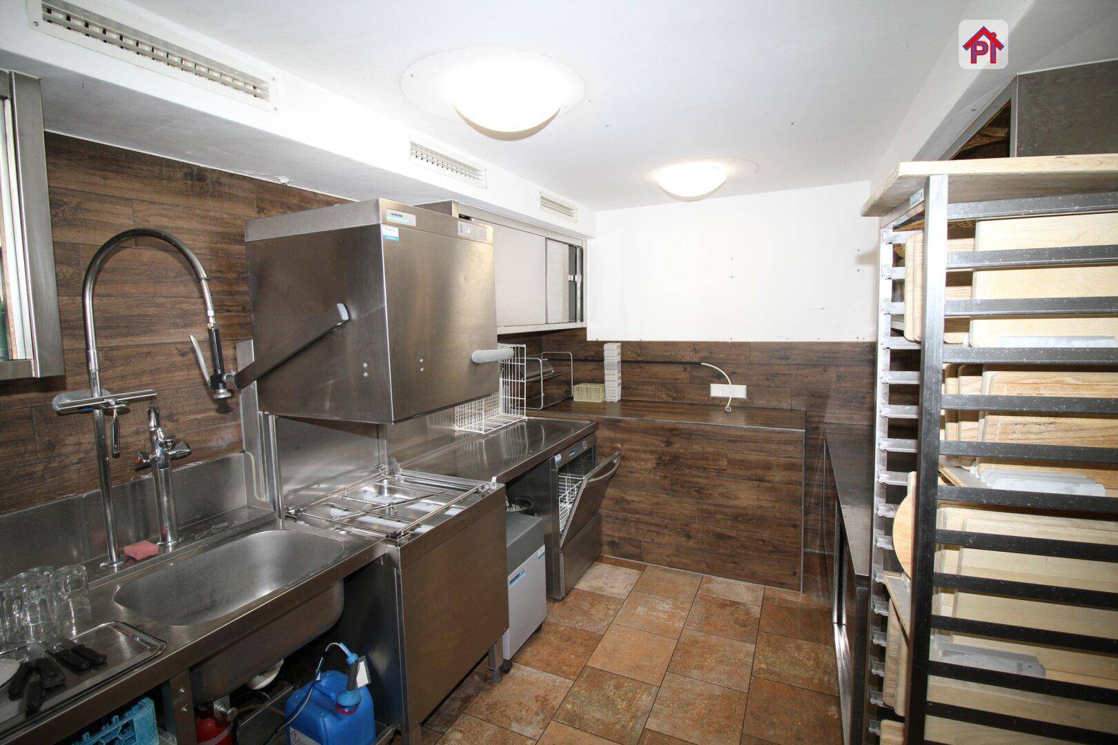 Professionelle Küche mit Edelstahleinrichtungen, gefliestem Boden und modernen Holzpaneelen an den Wänden.