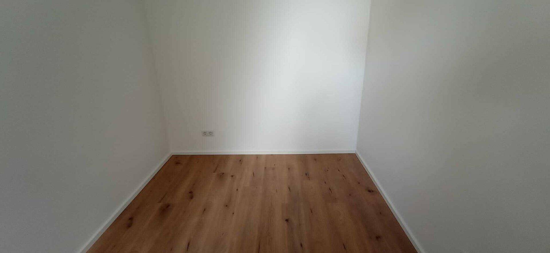 Kleiner, leerer Raum mit Holzboden und weißen Wänden, ideal als Abstellraum oder begehbarer Kleiderschrank.