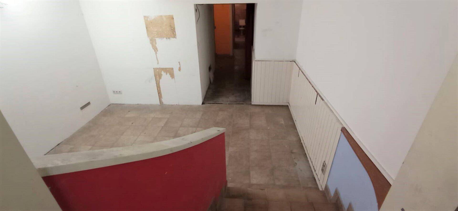 Eingangsbereich mit gefliestem Boden und weiß getäfelten Wänden, der zu einem hinteren Raum führt.