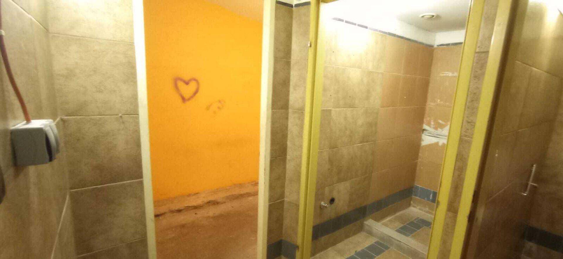 Badezimmerbereich mit braunen Fliesen und einer Duschkabine, die auf eine Renovierung wartet.
