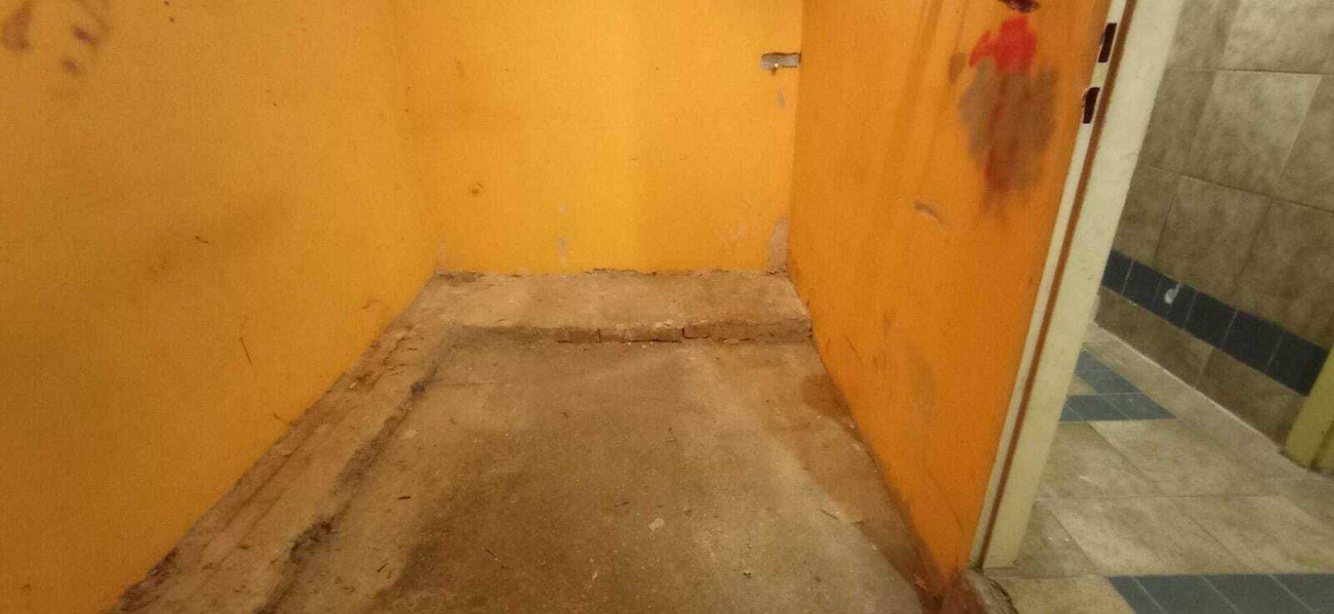 Kleiner Raum mit orangefarbenen Wänden und rohem Betonboden, der auf eine Neugestaltung wartet.