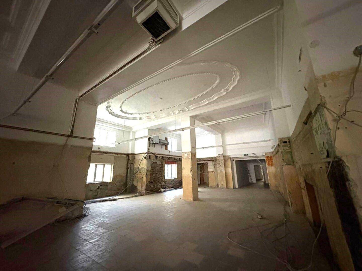 Großer, offener Gewerberaum im Rohbau mit hohen Decken und dekorativen Stuckelementen, bereit für den Ausbau.